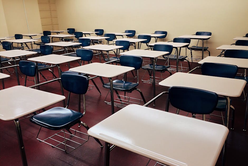 An empty classroom featuring neatly arranged desks and chairs ready for use.